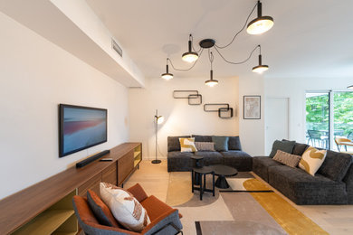 Diseño de salón abierto y blanco y madera contemporáneo grande con paredes blancas, suelo de madera clara y televisor colgado en la pared