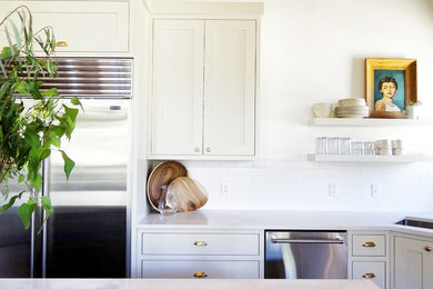 Mid-sized farmhouse l-shaped medium tone wood floor eat-in kitchen photo in Salt Lake City with a single-bowl sink, recessed-panel cabinets, white cabinets, quartz countertops, white backsplash, subway tile backsplash, stainless steel appliances and an island