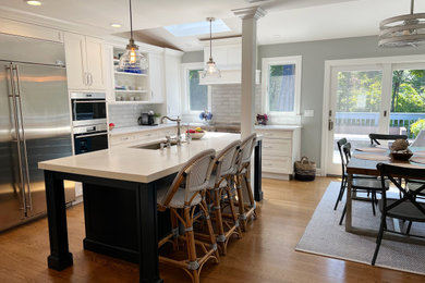 Mid-sized minimalist l-shaped light wood floor and brown floor eat-in kitchen photo in New York with an undermount sink, white cabinets, quartz countertops, white backsplash, ceramic backsplash, stainless steel appliances, an island and white countertops