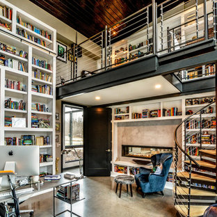 Inspiration for an expansive modern home office in Other with a library, grey walls, concrete floors, a two-sided fireplace, a concrete fireplace surround and a freestanding desk.