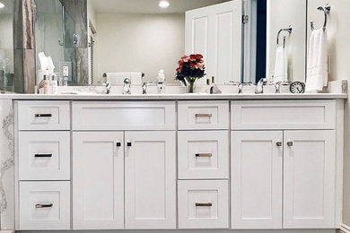 Mid-sized cottage chic master vinyl floor, brown floor and double-sink bathroom photo in Other with shaker cabinets, white cabinets, a one-piece toilet, white walls, a drop-in sink, quartz countertops, a hinged shower door, gray countertops and a built-in vanity