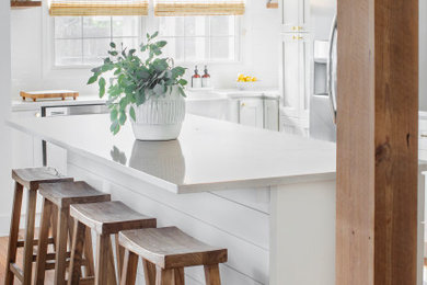 Kitchen - mid-sized transitional u-shaped medium tone wood floor and brown floor kitchen idea in Charleston with a farmhouse sink, shaker cabinets, white cabinets, stainless steel appliances, an island and white countertops