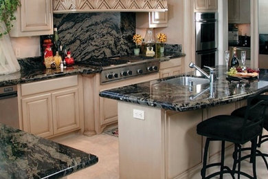 This is an example of a mid-sized l-shaped kitchen pantry in San Francisco with an undermount sink, raised-panel cabinets, light wood cabinets, granite benchtops, grey splashback, stone slab splashback, stainless steel appliances, ceramic floors and with island.