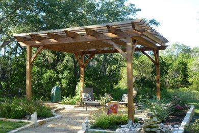Patio - mid-sized rustic backyard stone patio idea in Austin with a pergola
