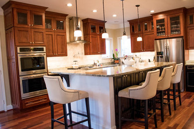 Large transitional l-shaped dark wood floor and brown floor enclosed kitchen photo in DC Metro with raised-panel cabinets, dark wood cabinets, an island, a double-bowl sink, stainless steel appliances, granite countertops, beige backsplash and limestone backsplash