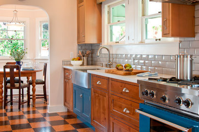 Elegant cork floor enclosed kitchen photo in San Diego with a farmhouse sink, shaker cabinets, medium tone wood cabinets, white backsplash, subway tile backsplash, colored appliances and no island