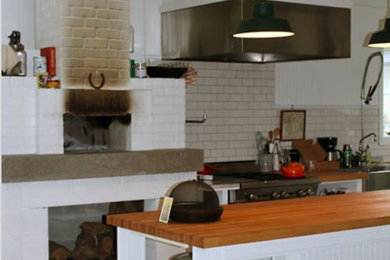 Inspiration for a mid-sized industrial single-wall concrete floor and gray floor open concept kitchen remodel in Seattle with a farmhouse sink, open cabinets, white cabinets, wood countertops, white backsplash, subway tile backsplash, stainless steel appliances and an island
