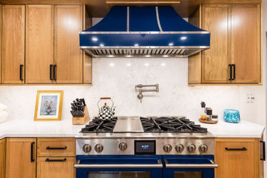 Example of a large minimalist l-shaped light wood floor, brown floor and exposed beam eat-in kitchen design in Columbus with a single-bowl sink, recessed-panel cabinets, light wood cabinets, quartz countertops, white backsplash, quartz backsplash, colored appliances, an island and white countertops
