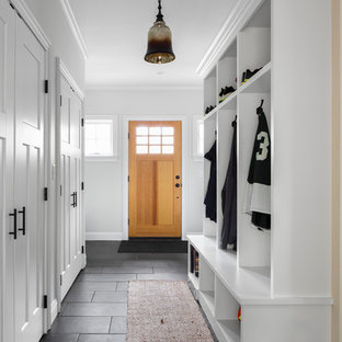 Esempio di un ingresso con anticamera tradizionale di medie dimensioni con pareti bianche, pavimento in ardesia, una porta singola e una porta in legno chiaro