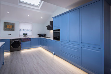 Ejemplo de cocina abovedada moderna de tamaño medio con fregadero sobremueble, armarios estilo shaker, puertas de armario azules, electrodomésticos con paneles, suelo gris y encimeras blancas