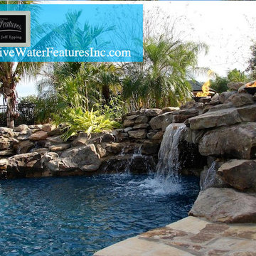 Tropical backyard room with pool waterfall, fireplace, and koi pond