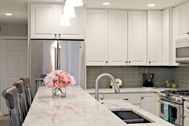 Eat-in kitchen - small transitional l-shaped light wood floor eat-in kitchen idea in Grand Rapids with a double-bowl sink, raised-panel cabinets, white cabinets, granite countertops, gray backsplash, subway tile backsplash, stainless steel appliances and an island