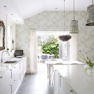 Modelo de cocina comedor actual con fregadero bajoencimera, armarios tipo vitrina, puertas de armario blancas y una isla