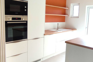 リールにある高級な小さなおしゃれなキッチン (インセット扉のキャビネット、白いキャビネット、ラミネートカウンター、茶色いキッチンカウンター) の写真