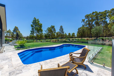 Inspiration for a large contemporary backyard custom-shaped pool in Newcastle - Maitland with with a pool and natural stone pavers.