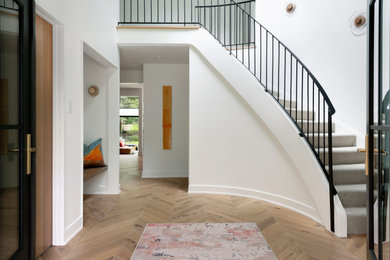 Example of a large trendy light wood floor and brown floor entryway design in Minneapolis with white walls and a black front door