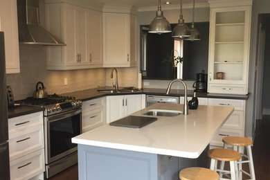 Inspiration for a mid-sized transitional l-shaped dark wood floor eat-in kitchen remodel in Toronto with an undermount sink, recessed-panel cabinets, white cabinets, stainless steel appliances, an island, marble countertops, beige backsplash and porcelain backsplash