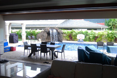 Example of a large classic backyard stone patio design in Hawaii with a pergola