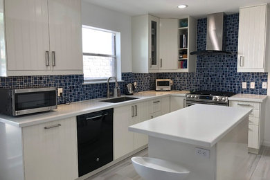 Mid-sized beach style ceramic tile and beige floor eat-in kitchen photo in Austin with an undermount sink, beaded inset cabinets, white cabinets, quartzite countertops, blue backsplash, ceramic backsplash, stainless steel appliances, an island and white countertops
