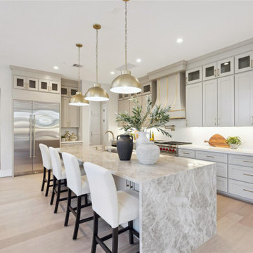 Custom kitchen with quartzite waterfall island and brass dome pendants