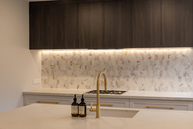 Inspiration for a mid-sized contemporary galley kitchen pantry in Newcastle - Maitland with an undermount sink, shaker cabinets, grey cabinets, quartz benchtops, multi-coloured splashback, mosaic tile splashback, black appliances, dark hardwood floors, with island, brown floor and grey benchtop.