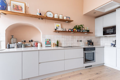 Design ideas for a large l-shaped kitchen/diner in Glasgow with grey cabinets, engineered stone countertops, cement tile splashback, light hardwood flooring, no island and white worktops.