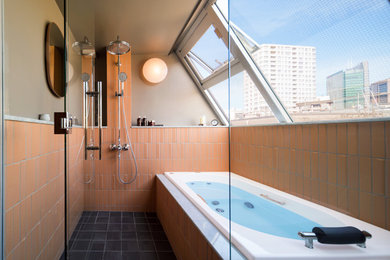 おしゃれな浴室 (オレンジのタイル、磁器タイル、オレンジの壁、磁器タイルの床、黒い床) の写真