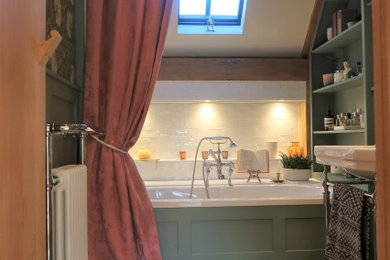 Design ideas for a medium sized traditional ensuite bathroom in Sussex with shaker cabinets, green cabinets, a built-in bath, a shower/bath combination, a two-piece toilet, white tiles, ceramic tiles, green walls, porcelain flooring, a console sink, brown floors, a shower curtain, feature lighting, a single sink, a freestanding vanity unit, a vaulted ceiling and panelled walls.