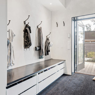 ストックホルムの中サイズの北欧スタイルのおしゃれなマッドルーム (白い壁、カーペット敷き、黒い床) の写真