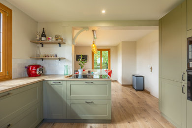 Inspiration pour une grande cuisine rustique en U fermée avec un évier 1 bac, des portes de placards vertess, un plan de travail en bois, une crédence blanche, une crédence en céramique, un électroménager en acier inoxydable, parquet clair, îlot, poutres apparentes et fenêtre au-dessus de l'évier.