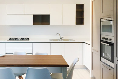 Foto di una cucina moderna di medie dimensioni con parquet chiaro e top bianco