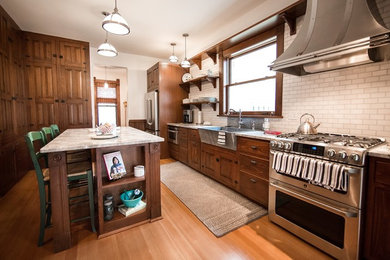 Kitchen - victorian u-shaped medium tone wood floor kitchen idea in Cedar Rapids with a farmhouse sink, beaded inset cabinets, medium tone wood cabinets, granite countertops, white backsplash, subway tile backsplash, stainless steel appliances and an island