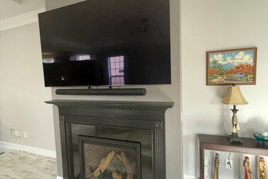 Inspiration for a contemporary laminate floor family room remodel in New York with gray walls, a standard fireplace, a plaster fireplace and a wall-mounted tv