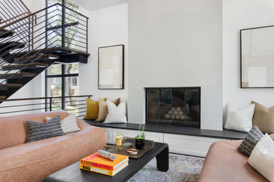 Example of a mid-sized minimalist open concept dark wood floor and brown floor living room design in Austin with white walls, a standard fireplace, a plaster fireplace and no tv