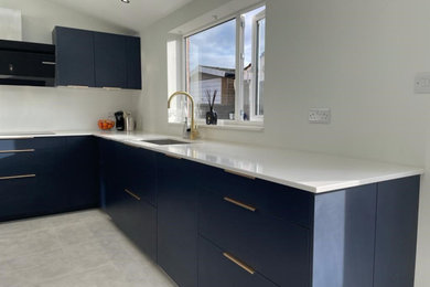 U-shaped kitchen in Other with a built-in sink, blue cabinets, white splashback, coloured appliances and white worktops.