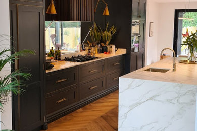 This is an example of a large retro single-wall open plan kitchen in London with marble worktops, mirror splashback and an island.