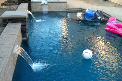 This is an example of a mid-sized traditional backyard rectangular lap pool in Orange County with natural stone pavers.