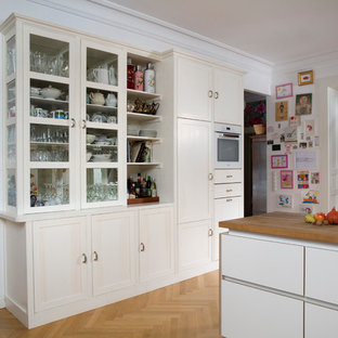 Large traditional kitchen pantry appliance - Kitchen pantry - large traditional medium tone wood floor kitchen pantry idea in Berlin with beaded inset cabinets, white cabinets, white backsplash, wood backsplash and white appliances