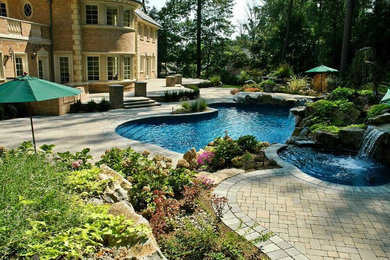 Modelo de piscinas y jacuzzis clásicos renovados grandes a medida en patio trasero con adoquines de piedra natural