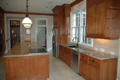 Amerikansk inredning av ett mellanstort kök, med en undermonterad diskho, luckor med infälld panel, skåp i mörkt trä, granitbänkskiva, rostfria vitvaror och en köksö