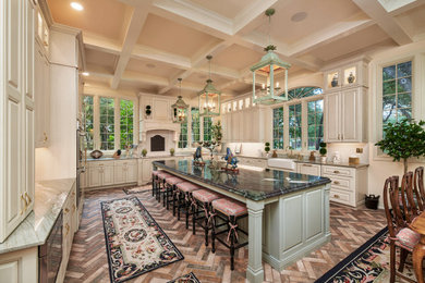 Example of a huge french country galley brick floor, red floor and coffered ceiling eat-in kitchen design in Other with a farmhouse sink, raised-panel cabinets, white cabinets, quartzite countertops, green backsplash, ceramic backsplash, paneled appliances, an island and green countertops
