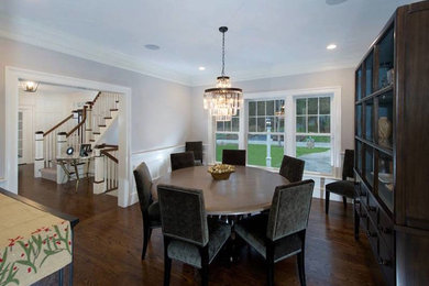 This is an example of a traditional dining room in Boston with white walls and dark hardwood floors.
