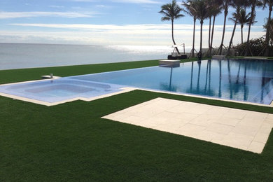 Inspiration for a large contemporary backyard rectangular infinity pool in Miami with concrete slab.