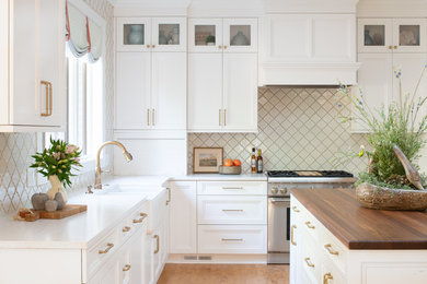 Large transitional l-shaped eat-in kitchen in Minneapolis with white cabinets, with island, a farmhouse sink, recessed-panel cabinets, beige splashback, medium hardwood floors, brown floor, white benchtop, quartz benchtops, mosaic tile splashback and stainless steel appliances.