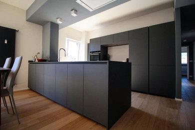 Idee per un cucina con isola centrale minimalista di medie dimensioni con lavello sottopiano, ante grigie, elettrodomestici in acciaio inossidabile e top grigio