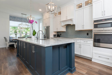 Example of a large transitional l-shaped eat-in kitchen design in Orlando with shaker cabinets, white cabinets, blue backsplash, glass tile backsplash, stainless steel appliances, an island, white countertops and quartz countertops