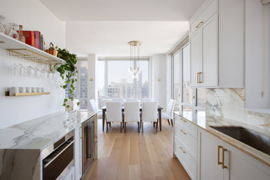 Eat-in kitchen - large transitional u-shaped light wood floor eat-in kitchen idea in New York with an undermount sink, shaker cabinets, white cabinets, marble countertops, white backsplash, marble backsplash, stainless steel appliances, no island and white countertops