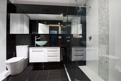 This is an example of a small modern master bathroom in Perth with a vessel sink, flat-panel cabinets, white cabinets, engineered quartz benchtops, a double shower, a one-piece toilet, white tile, porcelain tile, black walls and porcelain floors.