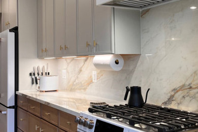 Example of a small minimalist single-wall laminate floor and beige floor eat-in kitchen design in Atlanta with beaded inset cabinets, white cabinets, marble countertops, beige backsplash, marble backsplash, stainless steel appliances, an island, white countertops and a drop-in sink