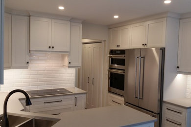 Inspiration for a transitional light wood floor kitchen remodel in Other with a double-bowl sink, shaker cabinets, white backsplash, cement tile backsplash, stainless steel appliances and quartz countertops